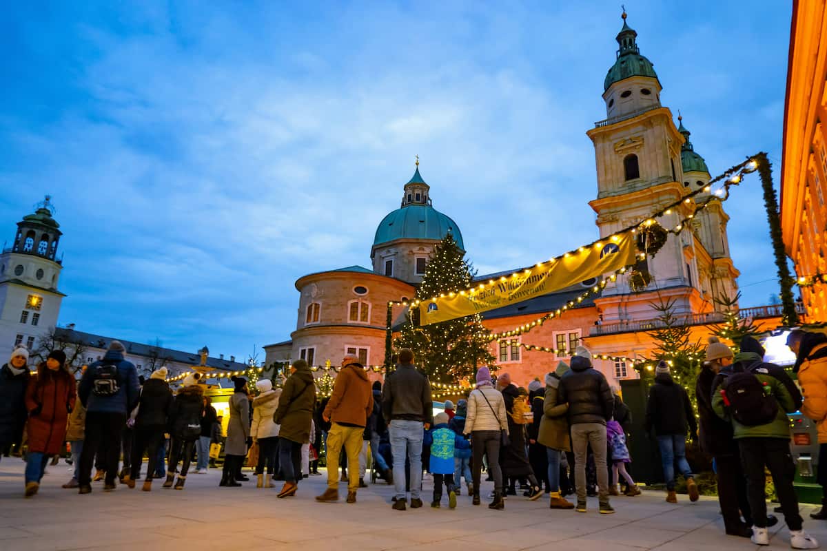 Salzburg Christmas market illuminated at dusk with festive lights in front of the historic Salzburg Cathedral
