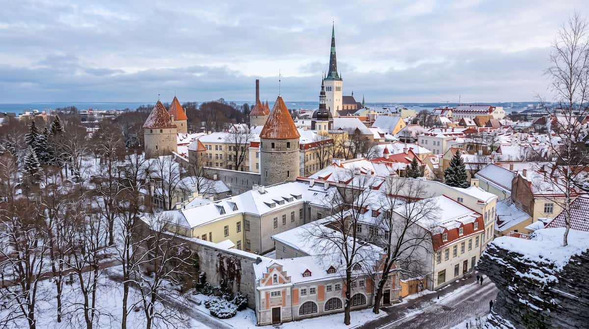 Panoramic view of snow-covered rooftops and church spires in Tallinn Old Town in winter.